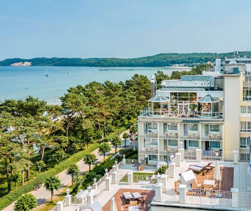 Aerial view of Rugard Thermal Strandhotel, with the sea, the coast and a pier in the background.