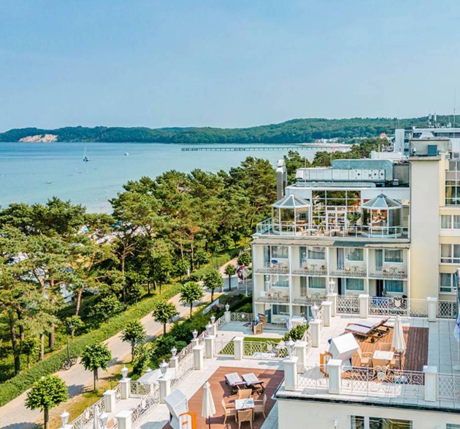 Aerial view of Rugard Thermal Strandhotel, with the sea, the coast and a pier in the background.