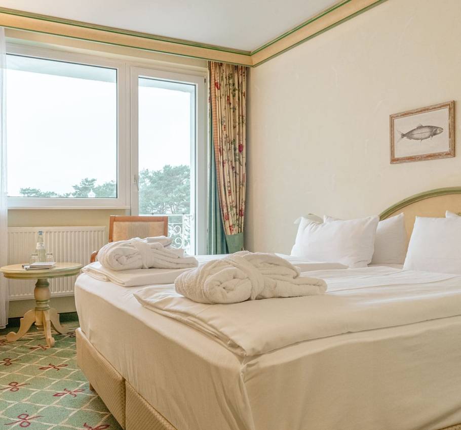 Doppelzimmer im Rugard Strandhotel Binz mit großem Bett, seitlichem Meerblick und Balkon.