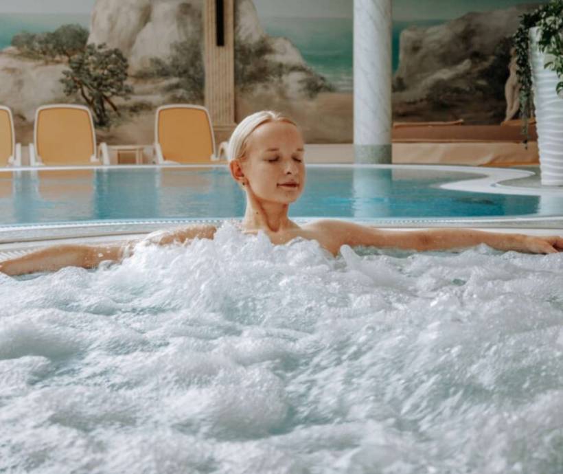 Eine Frau entspannt in einem Whirlpool in einem Wellnesshotel bei einem Angebot an der Ostsee.