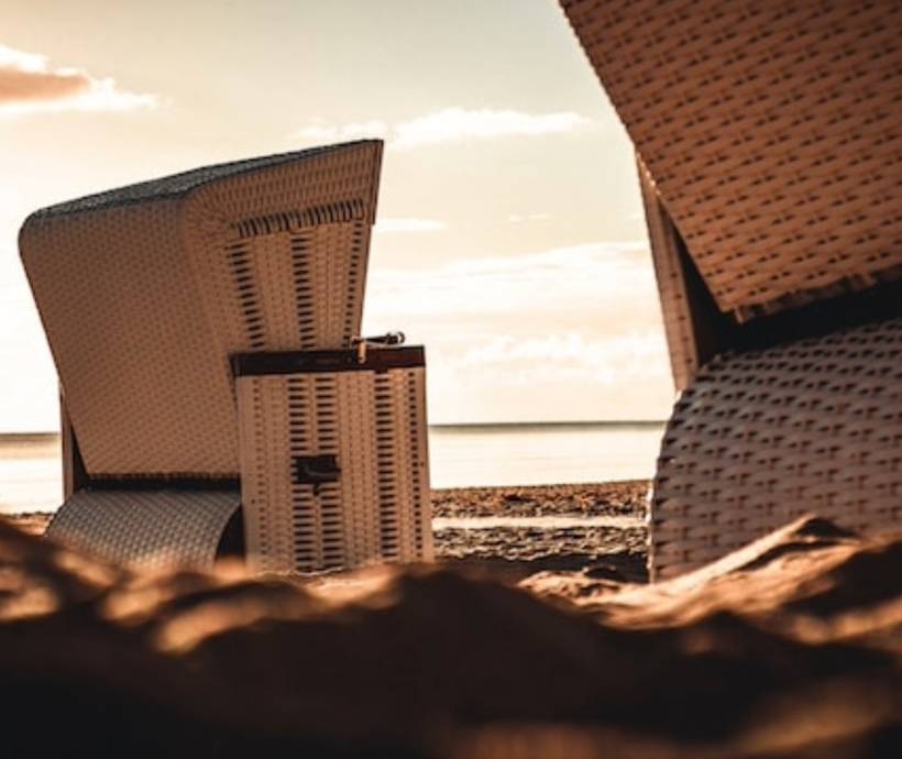 Detailaufnahme von Strandkörben am Ostseestrand bei Sonnenuntergang bei einem Wellnesshotel Angebot.