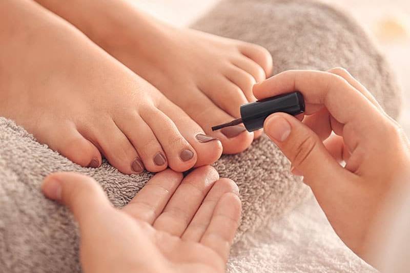 Zehennägel, die einen professionellen Nagellack erhalten.