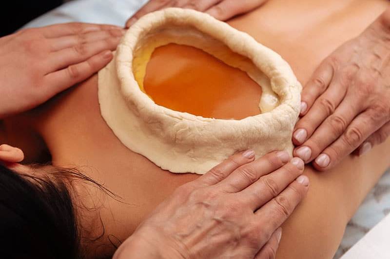 Ayurvedischer Teigring zur Schmerzbehandlung auf einem Rücken.