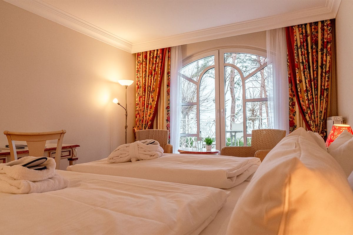 Brightly designed double room with a double bed, balcony view, and cozy lighting at Rugard Thermal Strandhotel