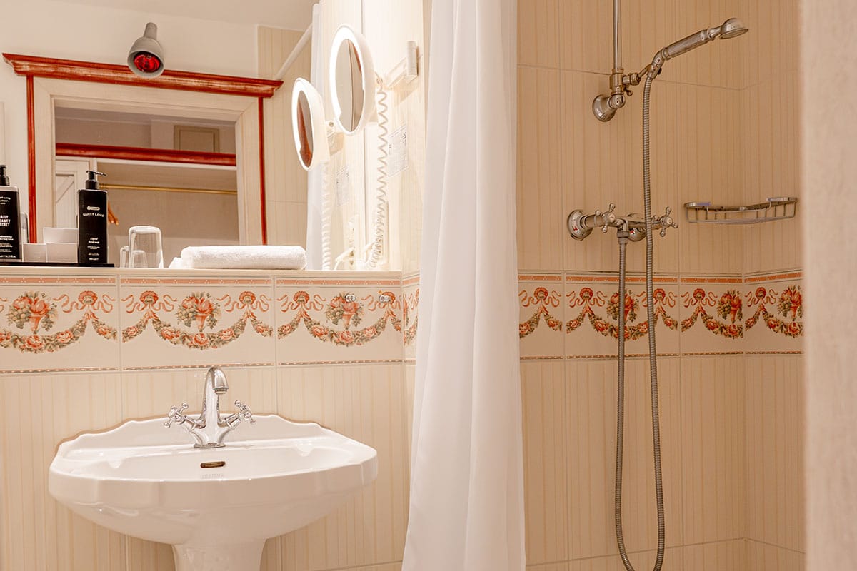 Stylish bathroom with shower, mirror, and classic tiles at Rugard Thermal Strandhotel Binz