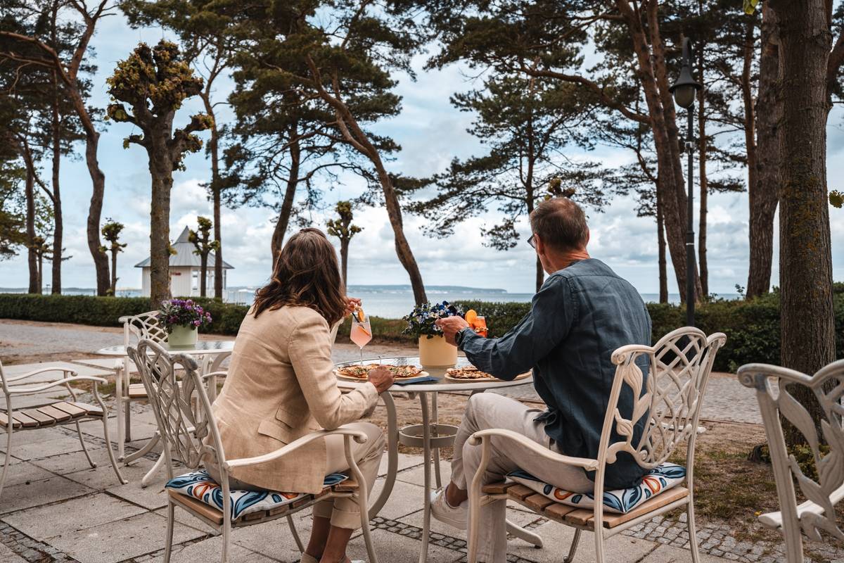 Drei Personen, von denen man nur ihre Hände sieht, stoßen mit Cocktails im Restaurant in Binz an.