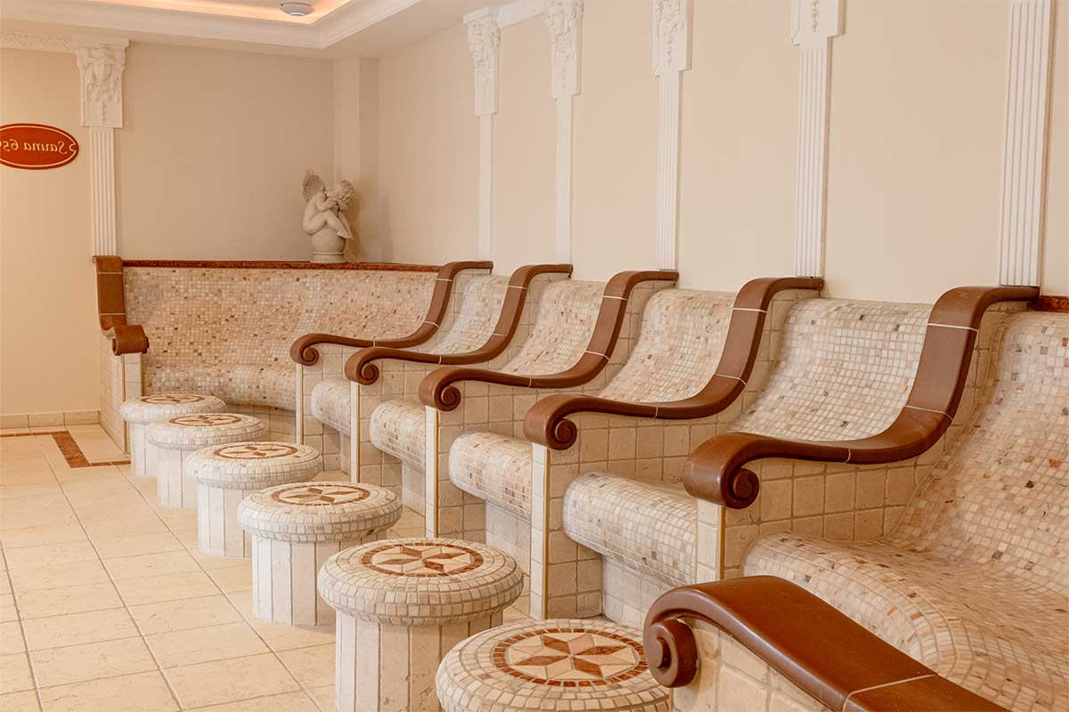View of heated mosaic loungers with armrests in the quiet tepidarium of the Rugard Thermal Strandhotel.